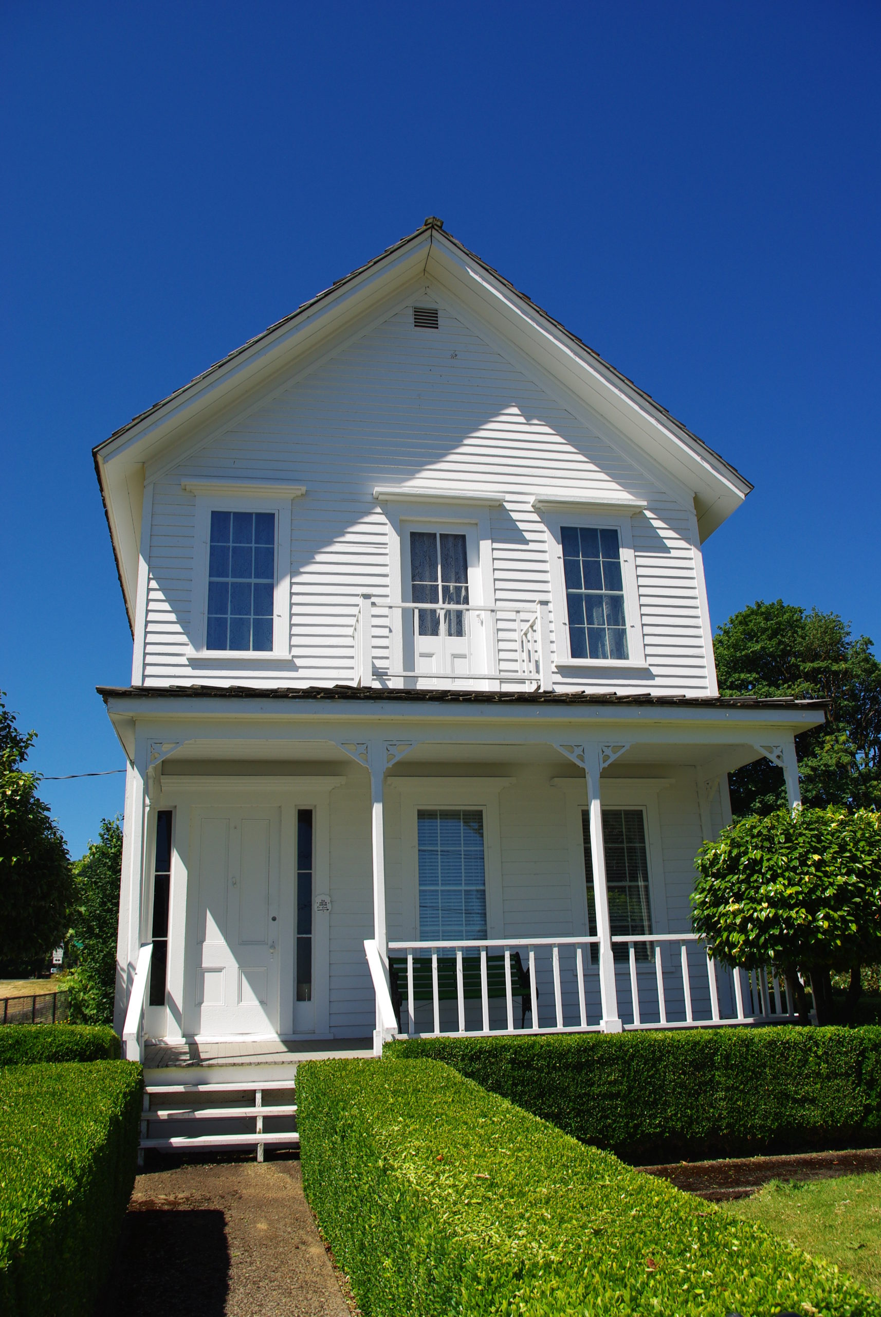 A white two-story historic home on a sunny day. 